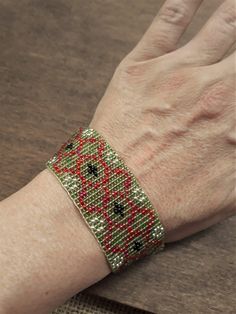 a woman's hand with a bracelet on her left wrist and red, green, and black beaded cuff