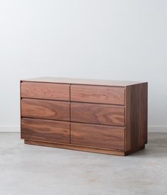 a large wooden dresser sitting on top of a cement floor next to a white wall