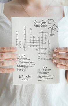 a woman holding up a crossword puzzle piece with wine glasses on it's back