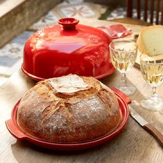 a loaf of bread sitting on top of a red plate next to a glass of wine