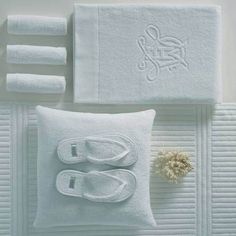 white towels and slippers are arranged on the floor next to a pillow with a flower