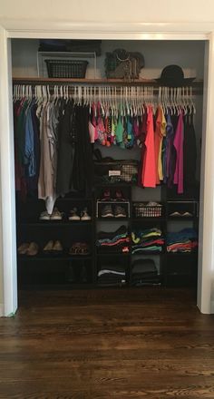 an open closet with clothes and shoes hanging on the rails, next to a wooden floor