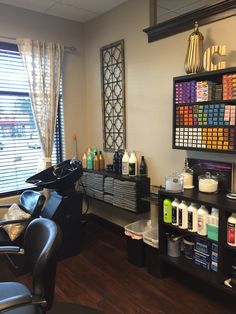 a salon with chairs, shelves and bottles on the wall in front of it's windows