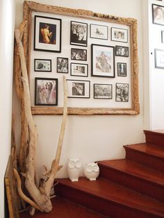 there are many pictures on the wall above the stairs in this house with wood steps