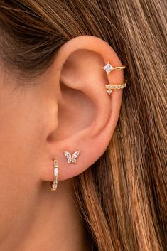 a woman wearing three different ear piercings on her left ear and the other one is gold