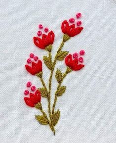 red flowers are embroidered on white fabric