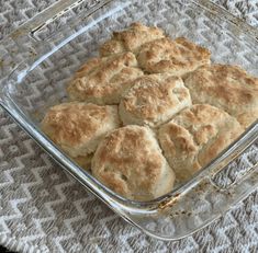 a glass casserole dish with biscuits in it on a tableclothed surface