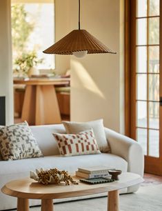 a living room filled with furniture and a lamp hanging over the top of a coffee table