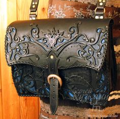 a black leather purse sitting on top of a wooden table next to a wood wall