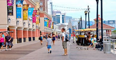 many people are walking on the boardwalk near buildings