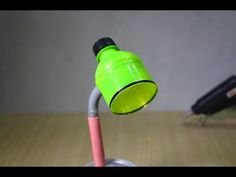 a green and pink light on top of a wooden table next to a black pen