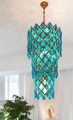 a blue chandelier hanging from the ceiling in a room with white walls and windows