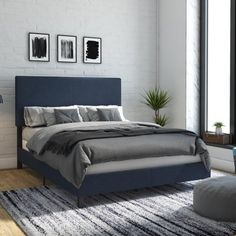 a bedroom with white brick walls and blue bedding in the center, along with a rug on the floor