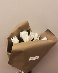 a bouquet of white tulips wrapped in brown paper