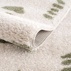 a white rug with green and gray designs on it's edges is laying on the floor