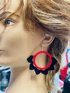 a mannequin head wearing red and black earrings