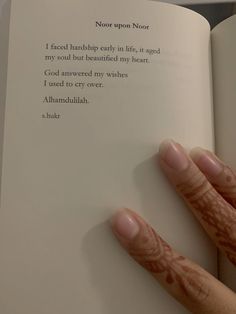 a person is holding an open book with writing on it and their hands are touching the pages