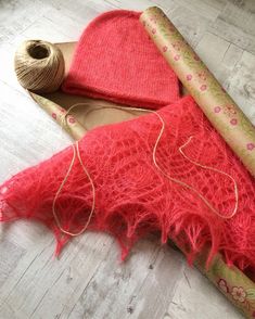 a pair of red shoes sitting on top of a wooden floor next to a roll of yarn