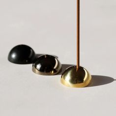 two black and gold balls on a white surface with a wooden stick in the foreground