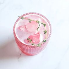 a pink cup filled with ice and flowers on top of a white countertop next to a marble surface