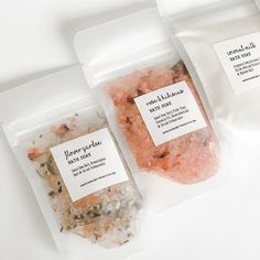 three bags of sea salts sitting on top of a white table next to each other