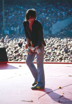 a man standing on top of a stage with a guitar in front of an audience