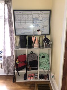 a white shelf filled with lots of purses and bags next to a window in a room