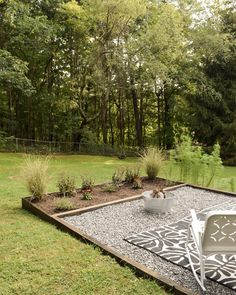 an outdoor patio with gravel and plants in the foreground, surrounded by wooded area