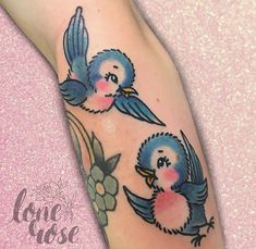 two blue birds are on the leg of a woman with pink flowers in her hair