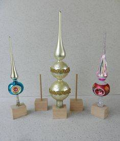 three different colored glass vases sitting on wooden stands in front of a white wall