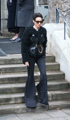 a woman standing on some steps with her hands in her pockets