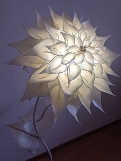 a large white paper flower is lit up in the dark by a light bulb that has been turned on