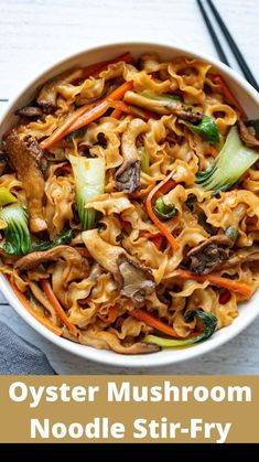 a bowl filled with noodles and vegetables next to chopsticks on a white table