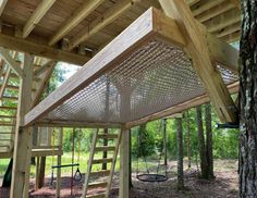 a wooden structure in the middle of a forest with ladders on it's sides