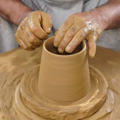 a man making a vase out of clay on a potter's wheel with his hands