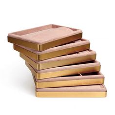 a stack of pink and gold trays sitting on top of each other in front of a white background