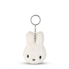 a white stuffed animal keychain hanging from a metal hook on a white background