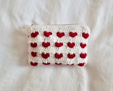 a crocheted red and white purse with hearts on it