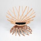 a sculpture made out of wooden sticks on a white surface with a black hole in the center