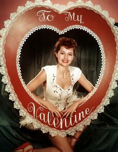 a woman posing in front of a heart with the words to my valentine written on it