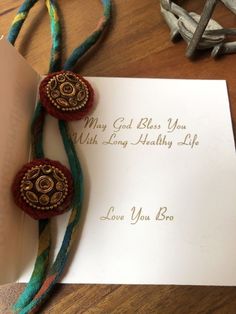 a card with two brooches attached to it on top of a wooden table