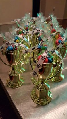 many small cups with candy in them on a silver table cloth covered tablecloth, along with ribbons and tags