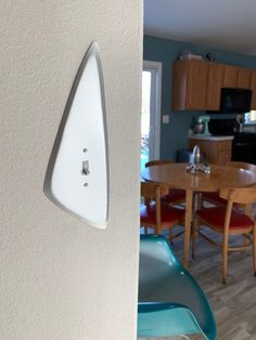 a wall mounted light switch in a kitchen next to a dining room table and chairs