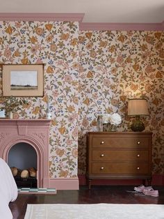 a bedroom with floral wallpaper and a fireplace in the corner next to a bed