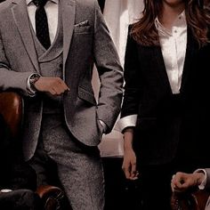 a man and woman standing next to each other in front of a desk with chairs