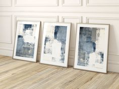 three framed art pieces sitting on top of a wooden floor