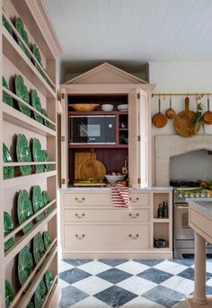 a kitchen with pink cabinets and green plates on the counter top, in front of an oven