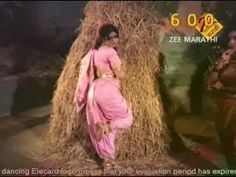 a woman standing next to a pile of hay