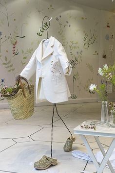 a white coat and shoes on display in a room with wallpapered walls,