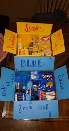 a blue box filled with lots of food and candy sitting on top of a wooden table